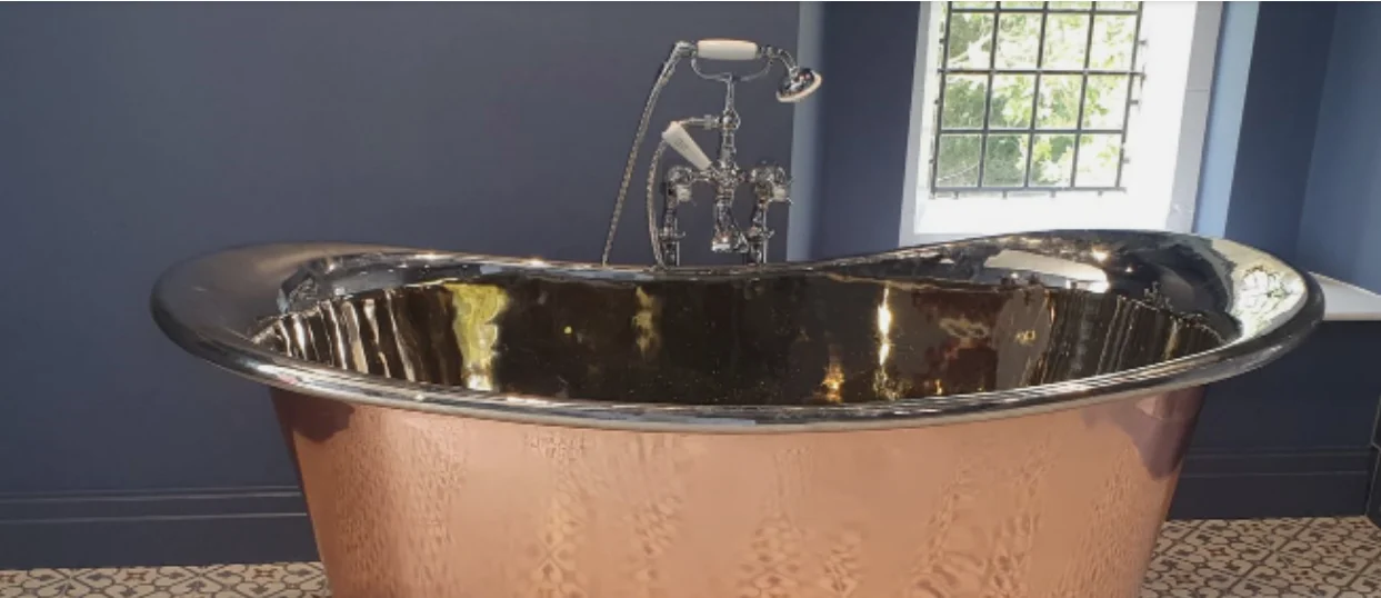 A copper roll-top bath with chrome taps, fitted by Elegance